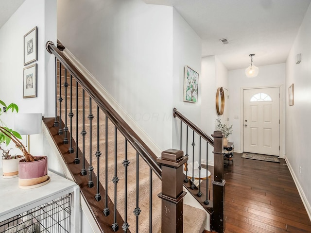 foyer entrance with baseboards, visible vents, and dark wood-type flooring