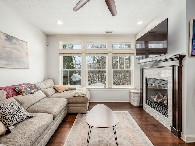 living area with dark wood-style floors, a textured ceiling, a tiled fireplace, and visible vents