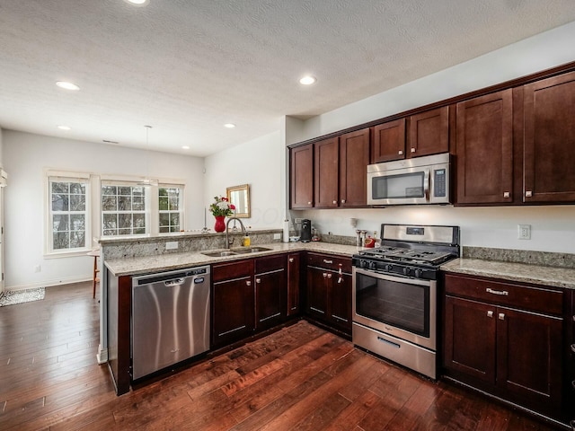 kitchen featuring stainless steel appliances, a sink, a peninsula, and light stone counters