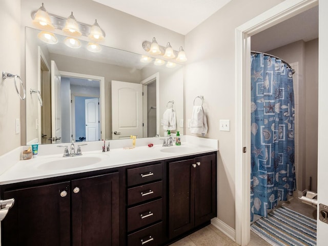 full bathroom featuring double vanity, tile patterned flooring, baseboards, and a sink