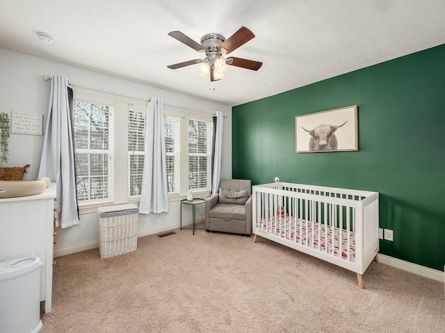 bedroom with light carpet, a nursery area, visible vents, and baseboards