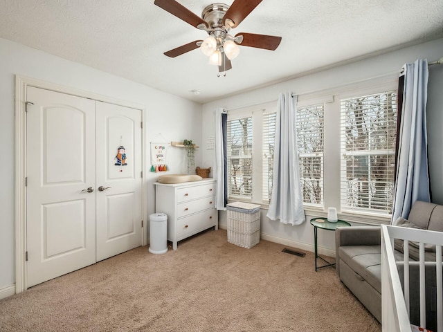 bedroom with a ceiling fan, visible vents, light carpet, and a textured ceiling