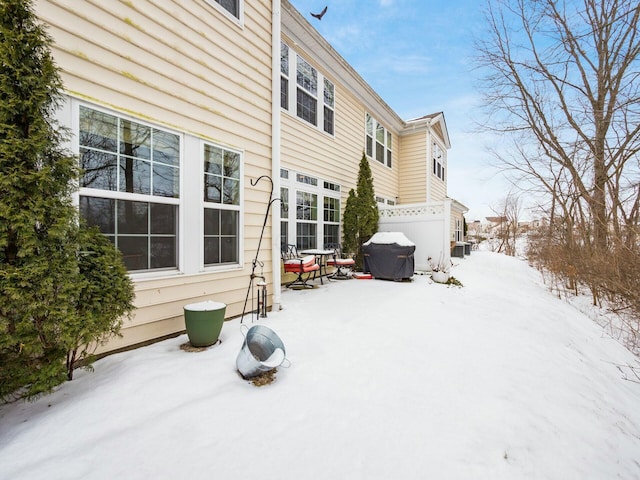 snow covered house featuring central AC and fence