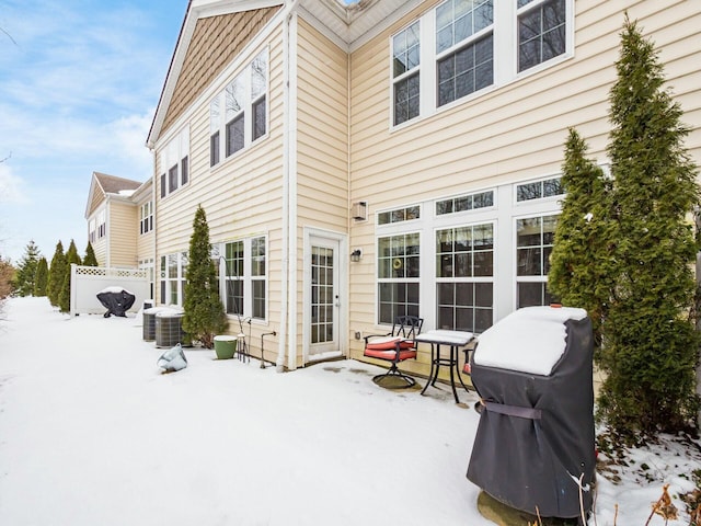 snow covered property featuring fence and central AC unit