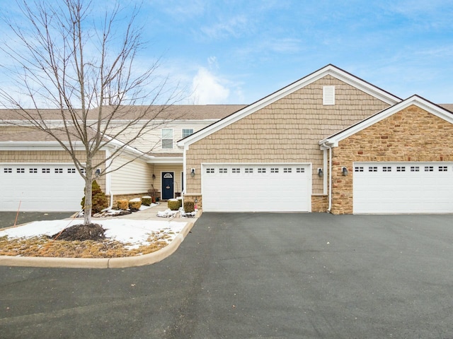 view of front of home featuring stone siding, aphalt driveway, and an attached garage