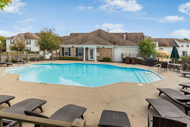 community pool with a residential view, fence, a patio, and an outdoor structure