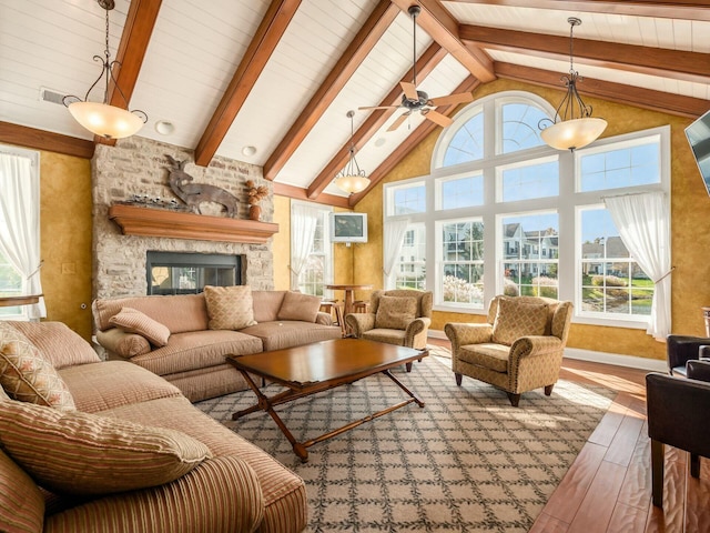 sunroom with lofted ceiling with beams, ceiling fan, and a stone fireplace