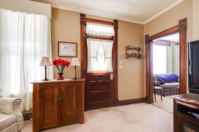 foyer featuring light carpet, baseboards, a wealth of natural light, and crown molding