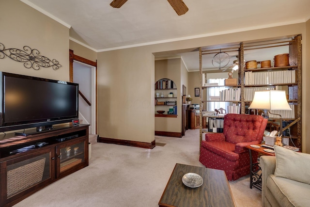 living area with ornamental molding, light colored carpet, a ceiling fan, and baseboards