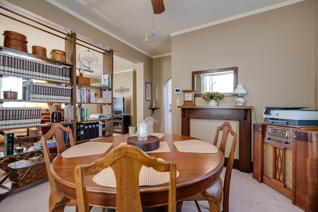 dining space featuring ornamental molding, arched walkways, and light colored carpet