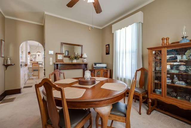 dining space with visible vents, arched walkways, a ceiling fan, light colored carpet, and crown molding