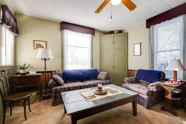 living area with light carpet, ceiling fan, wainscoting, and wooden walls