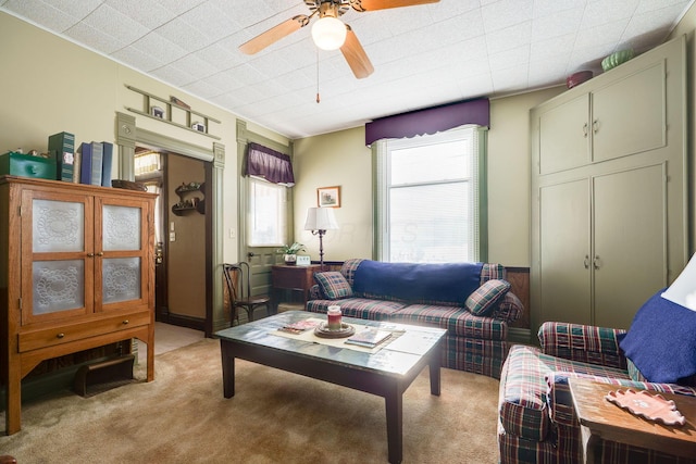 living room featuring light carpet, ceiling fan, and wainscoting