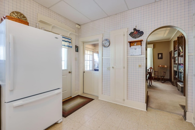 kitchen featuring light floors, arched walkways, and freestanding refrigerator