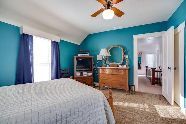 bedroom with multiple windows, visible vents, vaulted ceiling, and carpet flooring