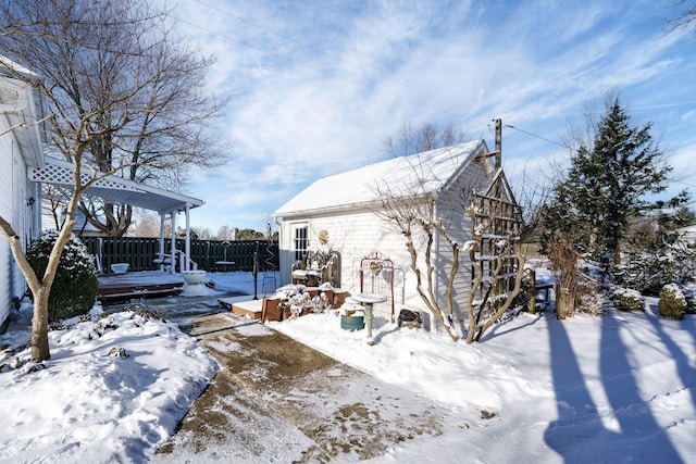 view of snow covered exterior with fence and an outdoor structure