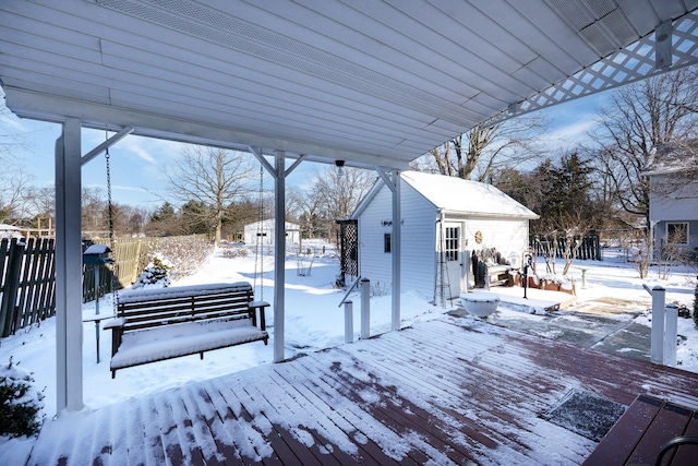 snow covered deck featuring fence and an outbuilding