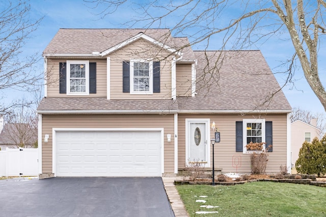 view of front of house with driveway, roof with shingles, an attached garage, fence, and a front lawn