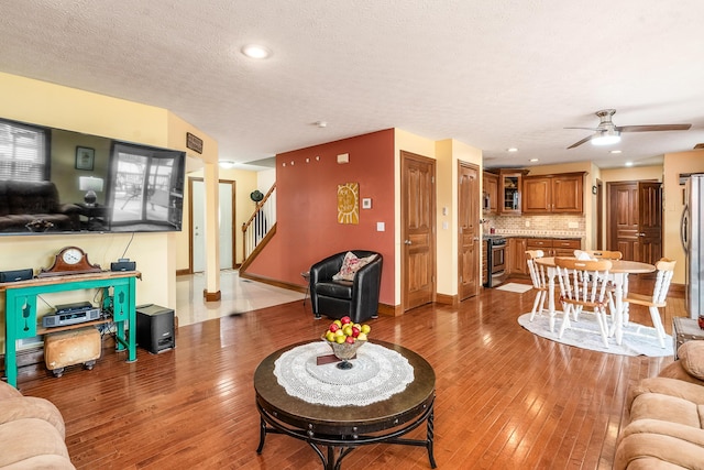 living area with baseboards, light wood-style flooring, a textured ceiling, and stairs