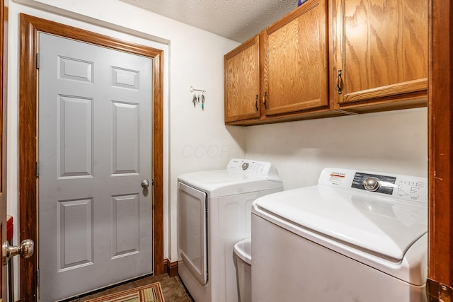 clothes washing area with cabinet space, washer and clothes dryer, and a textured ceiling