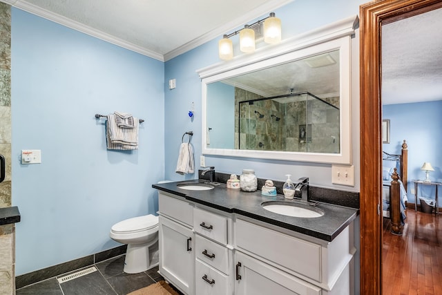 full bathroom featuring double vanity, a stall shower, crown molding, and a sink