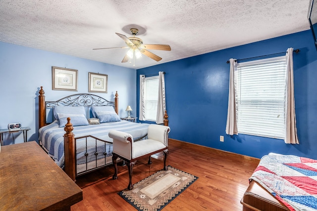 bedroom featuring a textured ceiling, dark wood finished floors, and a ceiling fan