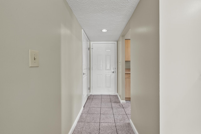 hallway featuring baseboards and a textured ceiling