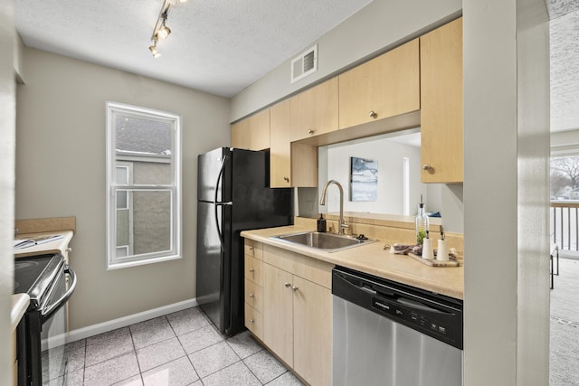 kitchen featuring black appliances, light brown cabinetry, a sink, and light countertops