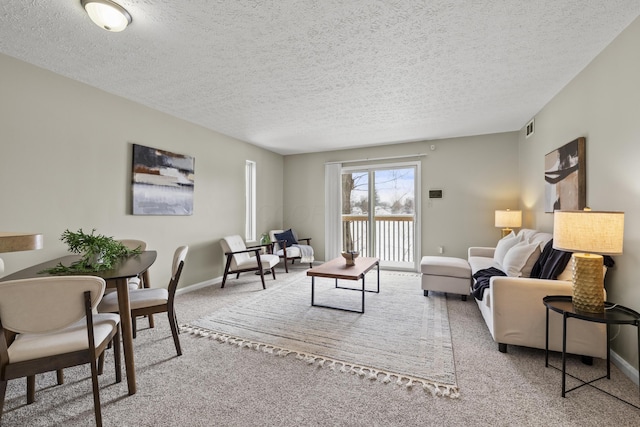 living area featuring baseboards, a textured ceiling, visible vents, and carpet flooring