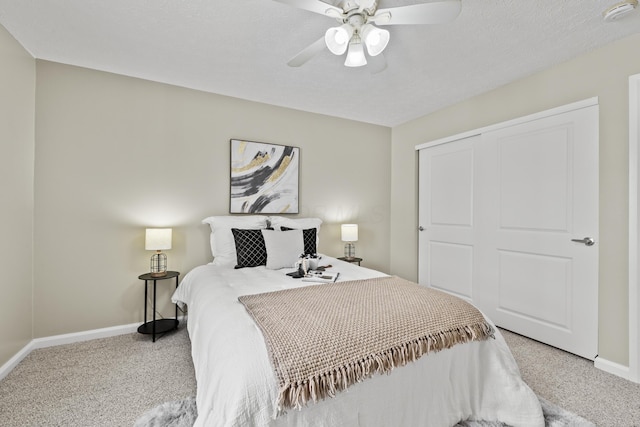 carpeted bedroom featuring ceiling fan, a closet, a textured ceiling, and baseboards