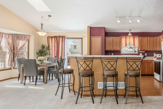 kitchen with brown cabinets, range with electric stovetop, light countertops, hanging light fixtures, and a kitchen breakfast bar