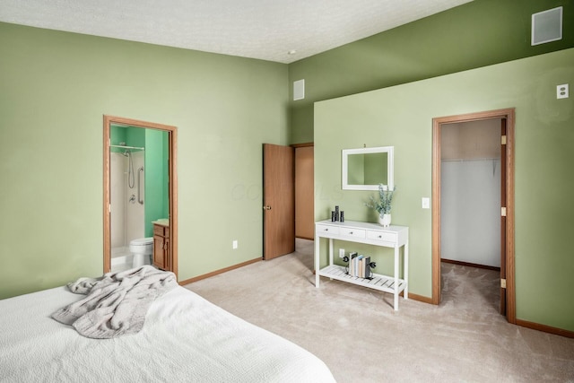 bedroom with a walk in closet, lofted ceiling, a closet, light colored carpet, and baseboards