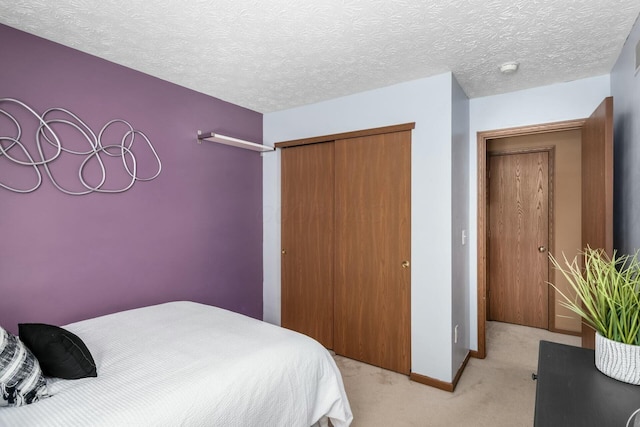 bedroom featuring light carpet, a closet, a textured ceiling, and baseboards