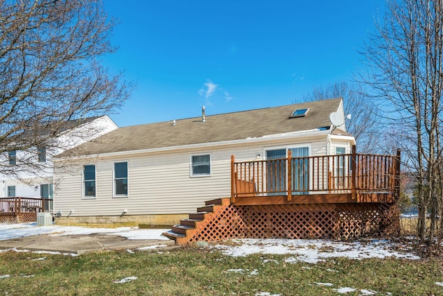 snow covered rear of property with a deck