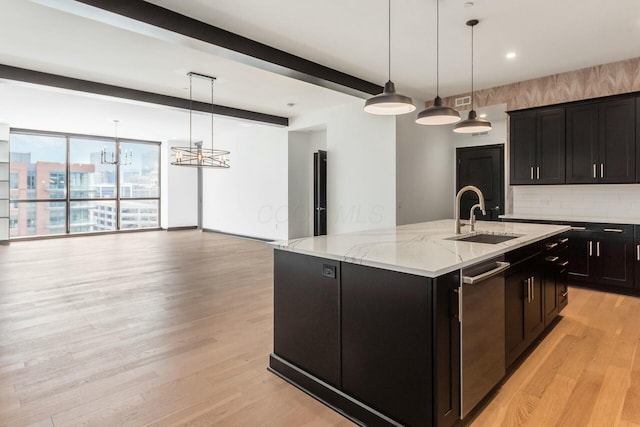 kitchen featuring light wood-style floors, a center island with sink, pendant lighting, and a sink