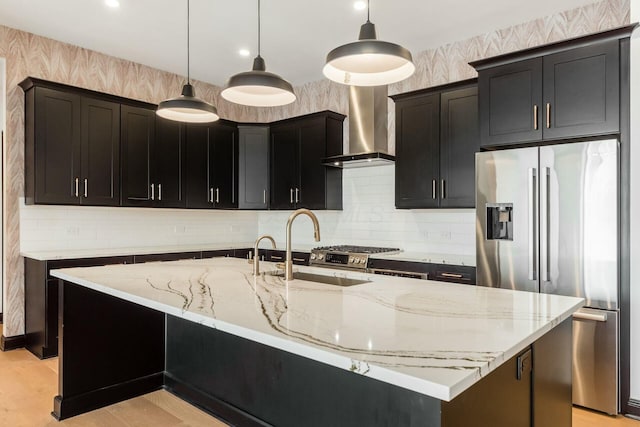 kitchen featuring stainless steel appliances, hanging light fixtures, an island with sink, and wallpapered walls