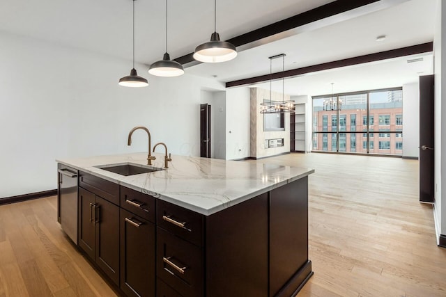 kitchen with decorative light fixtures, light wood-style flooring, open floor plan, a sink, and an island with sink