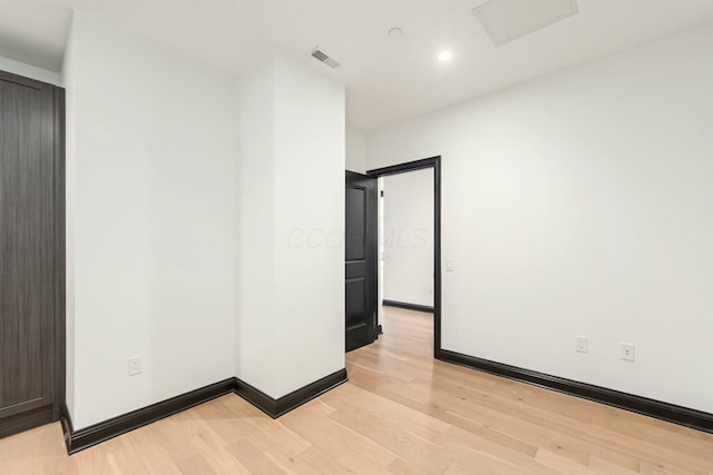 empty room featuring light wood-style flooring, visible vents, and baseboards