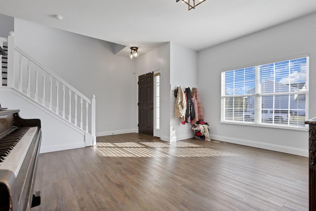 foyer entrance with stairway, baseboards, and wood finished floors