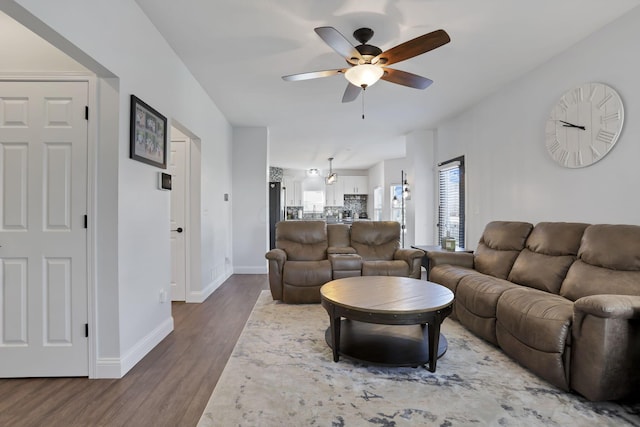 living room featuring ceiling fan, baseboards, and wood finished floors