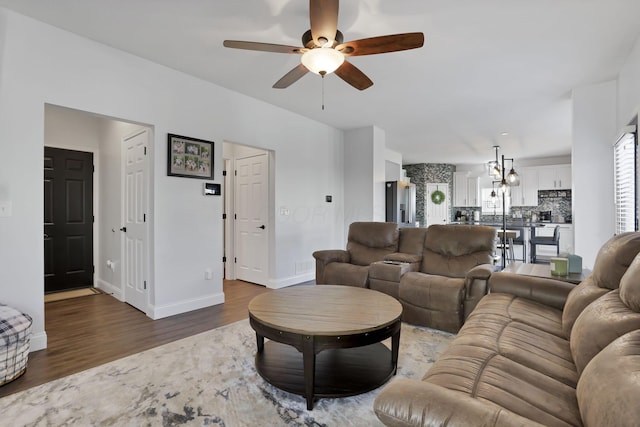 living room with a ceiling fan, baseboards, and wood finished floors