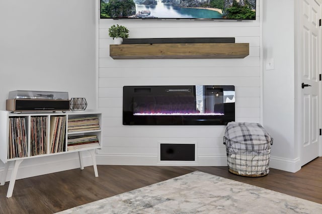 room details featuring wood finished floors, a glass covered fireplace, and baseboards