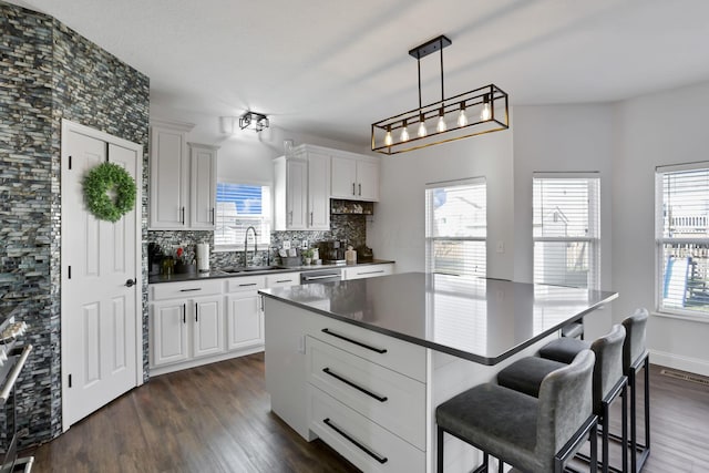 kitchen with dark countertops, tasteful backsplash, dark wood-type flooring, and a sink