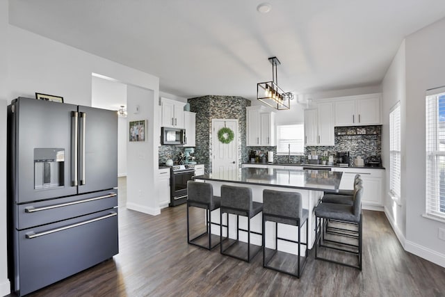 kitchen featuring stainless steel appliances, white cabinets, a kitchen breakfast bar, and dark wood-style floors