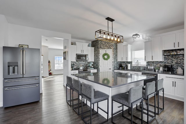 kitchen featuring dark countertops, appliances with stainless steel finishes, dark wood-style flooring, and backsplash