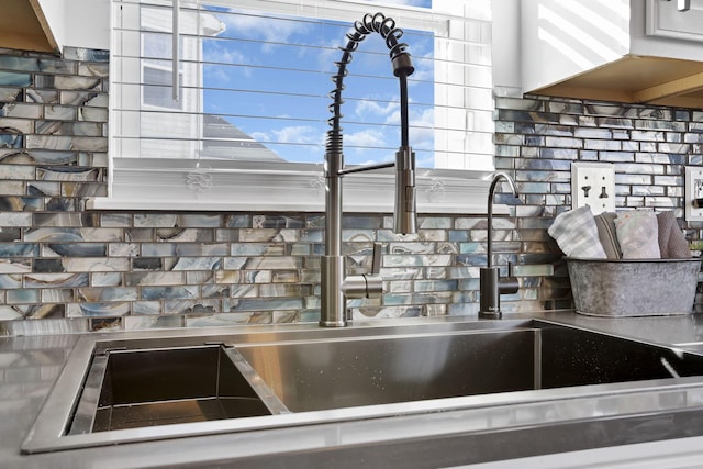 interior details featuring stainless steel counters, a sink, and decorative backsplash