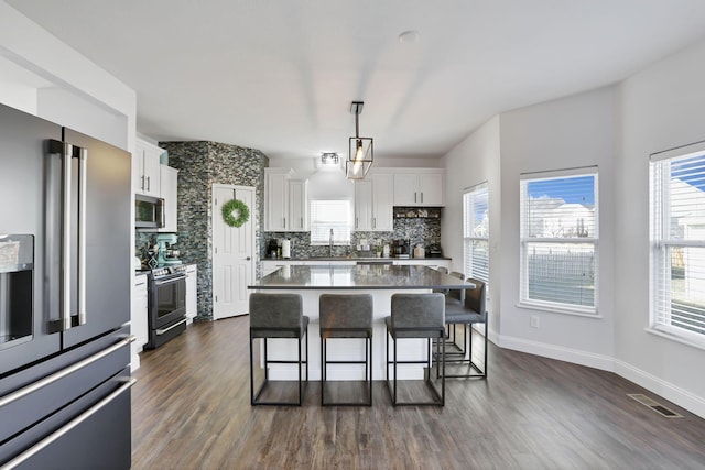 kitchen featuring a breakfast bar, tasteful backsplash, visible vents, appliances with stainless steel finishes, and white cabinets