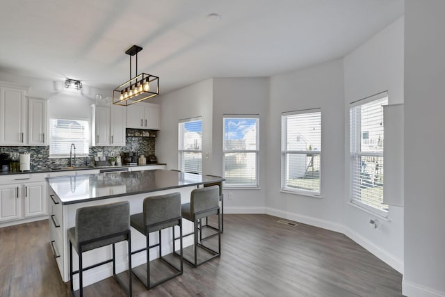 kitchen with dark countertops, tasteful backsplash, visible vents, and a breakfast bar