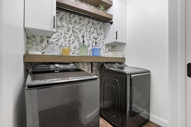 laundry area featuring cabinet space, baseboards, wood finished floors, and independent washer and dryer