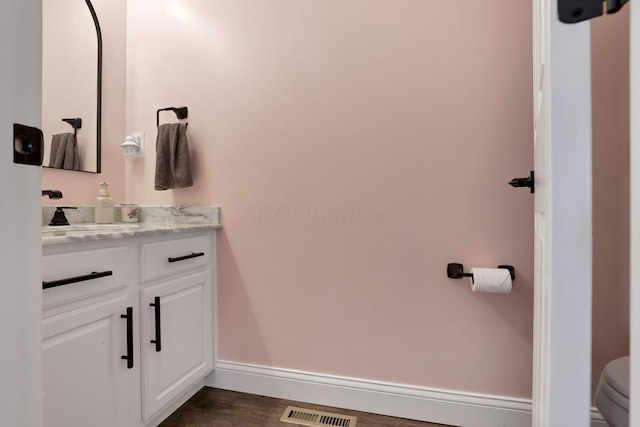 bathroom with baseboards, visible vents, toilet, wood finished floors, and vanity